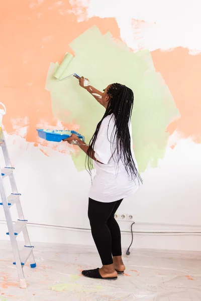 Reparaţii în apartament. O tânără fericită pictează peretele cu vopsea . — Fotografie, imagine de stoc