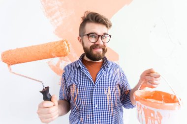Evin içini boya silindiriyle boyayan komik bir adam. Dekorasyon, yenileme, apartman onarımı ve ferahlatıcı konsept.