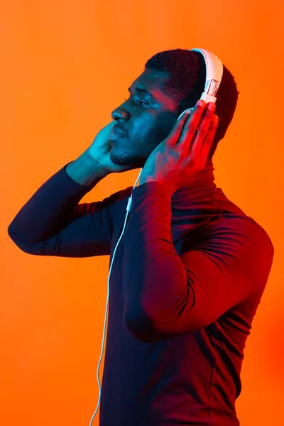 Νεαροί αφροαμερικάνοι που ακούνε μουσική με ακουστικά σε νέον φως. Ανδρικό πορτρέτο. Έννοια των ανθρώπινων συναισθημάτων, έκφραση προσώπου, διακοπές ή Σαββατοκύριακο, χόμπι, — Φωτογραφία Αρχείου