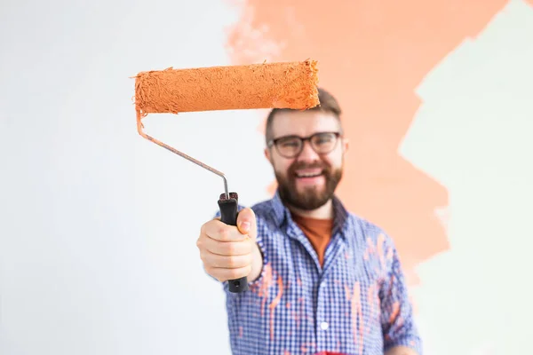 Renovation, redecoration and repair concept - Cheerful guy painting wall in new home. — Stock Photo, Image