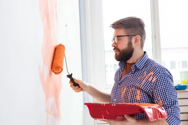 Riparazione nell'appartamento. L'uomo dipinge il muro con vernice . — Foto Stock