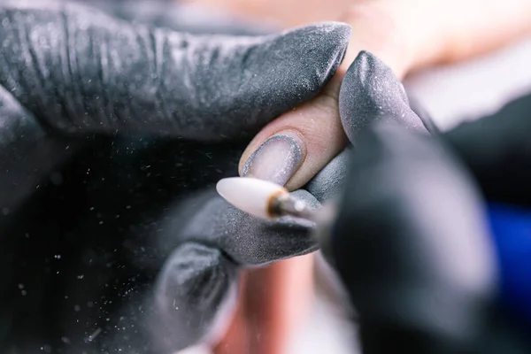 女主人在美容院修指甲的过程中使用了电动机器来去除指甲油。特写镜头硬件修指甲。手部护理的概念。用铣刀清洗指甲的女修指甲师 — 图库照片