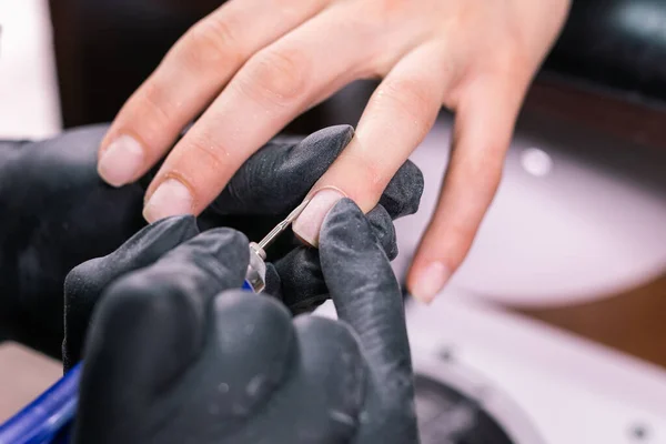 Крупный план аппаратного маникюра в салоне красоты. Маникюр применяет электрическую дрель для ногтей к маникюру на женских пальцах . — стоковое фото
