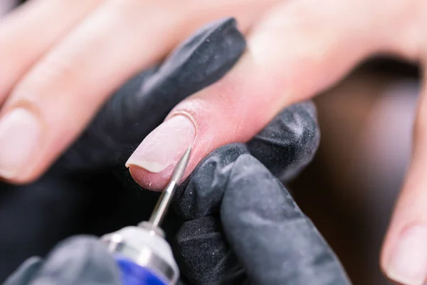 Manicure hardware in un salone di bellezza. manicure femminile sta applicando trapano lima elettrica per unghie per manicure sulle dita femminili. Manicure meccanica primo piano. Concetto cura del corpo. — Foto Stock