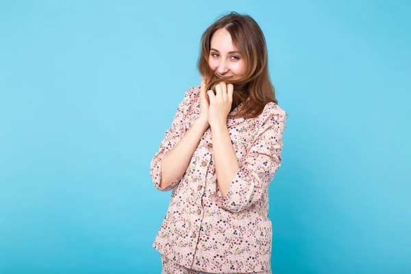 Rapariga sorridente em pijama casa desgaste posando enquanto descansa em casa isolado no fundo azul estúdio retrato. Relaxe conceito de estilo de vida de bom humor . — Fotografia de Stock