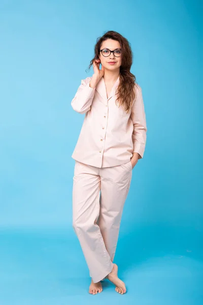 Rapariga sorridente em pijama casa desgaste posando enquanto descansa em casa isolado no fundo azul estúdio retrato. Relaxe conceito de estilo de vida de bom humor . — Fotografia de Stock