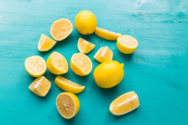 Taze kesilmiş yarım limon ve tüm limonlar kırsal akuamarin renk tahtalarında. Yaz, vitaminler ve tazelik konsepti.