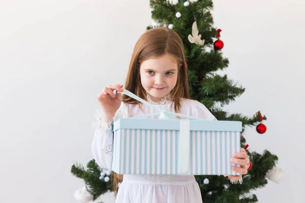 Mädchen öffnet Geschenkbox neben Weihnachtsbaum Feiertage, Weihnachten und Geschenke. — Stockfoto