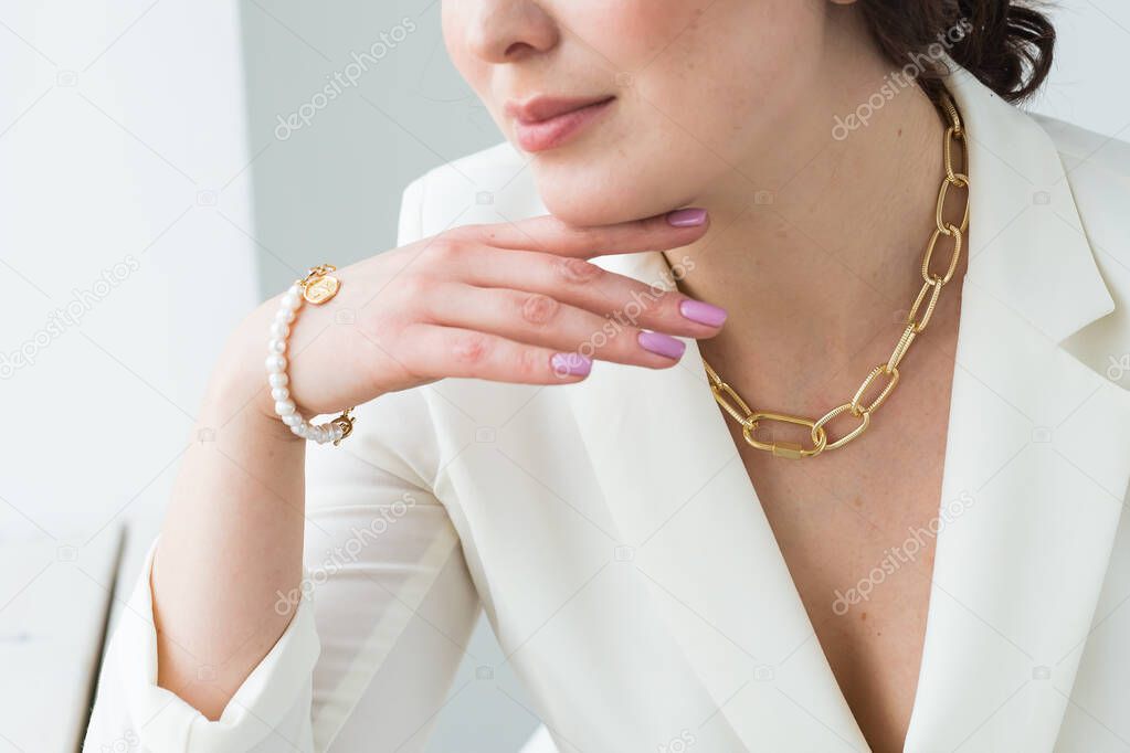 Close-up of woman wearing a gold necklace and bracelet. Jewelry, bijouterie and accessories concept.