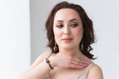 Zarif saç stili, lüks mücevherleri ve bijouterisi olan güzel bir genç kadının yakın plan portresi..