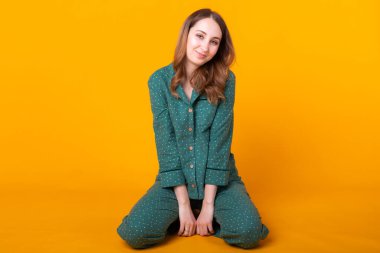 Pijamalı gülümseyen genç kız, sarı arka plan stüdyo resminde dinlenirken poz veriyor. Rahatla iyi ruh hali yaşam tarzı konsepti.