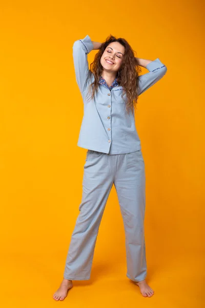 Chica joven sonriente en pijama ropa de casa posando mientras descansa en casa aislado en retrato de estudio de fondo amarillo. Relajarse concepto de buen humor estilo de vida . — Foto de Stock