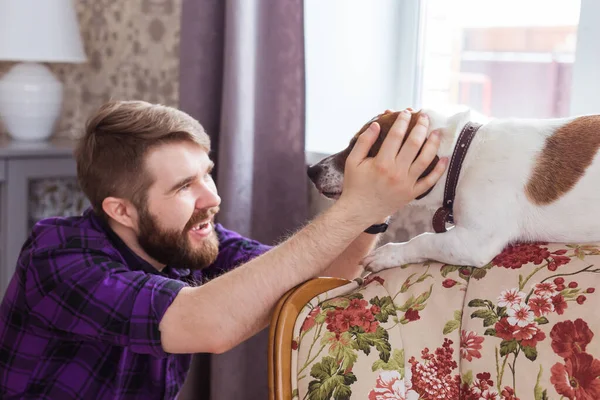 Feliz joven sentado con su perro en casa. Propietario de mascotas, animales y concepto de amistad . — Foto de Stock