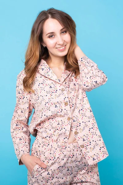 Rapariga sorridente em pijama casa desgaste posando enquanto descansa em casa isolado no fundo azul estúdio retrato. Relaxe conceito de estilo de vida de bom humor . — Fotografia de Stock