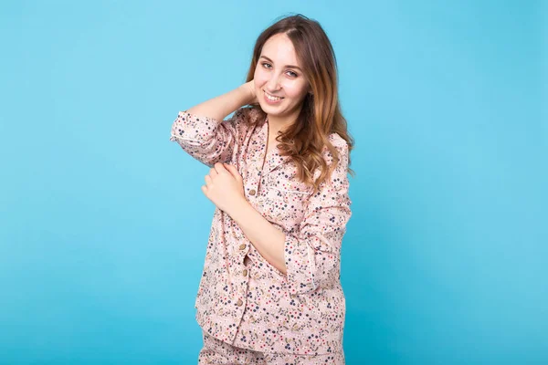 Jeune fille souriante en pyjama vêtements à la maison posant tout en se reposant à la maison isolé sur fond bleu portrait studio. Détendez-vous concept de style de vie de bonne humeur . — Photo