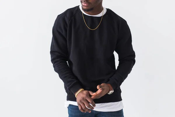 Close-up van zwarte man gekleed in jeans en sweatshirt op witte achtergrond. Straatmode en moderne jeugdcultuur. — Stockfoto