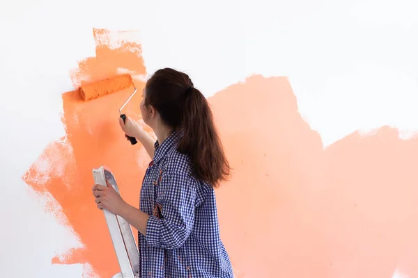 Duvarı boyayan güzel bir kadın. Tadilat, dekorasyon ve onarım. Boşluğu kopyala. — Stok fotoğraf
