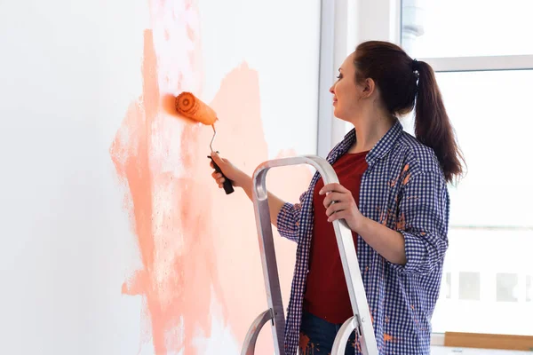 Yeni dairesinde duvar boyayan güzel bir kadın. Yenileme ve dekorasyon konsepti. — Stok fotoğraf