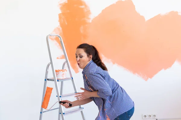 Bailando mujer divertida pintando las paredes de un nuevo hogar. Concepto de renovación, reparación y redecoración . — Foto de Stock