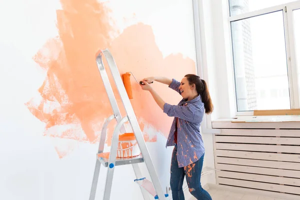 Yeni dairesinde duvar boyayan mutlu genç bir kadın. Yenileme, dekorasyon ve onarım konsepti. — Stok fotoğraf