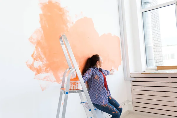 Riparazione nell'appartamento. Donna felice dipinge il muro con vernice. — Foto Stock