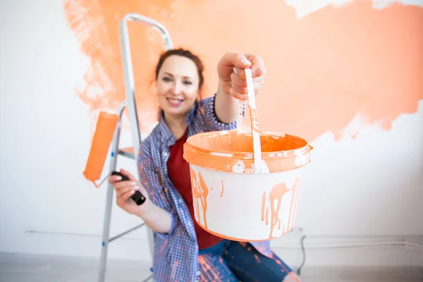 Mujer joven divertida con rodillo de pintura en el interior. Redecoración, renovación, reparación de apartamentos y concepto de refresco . — Foto de Stock