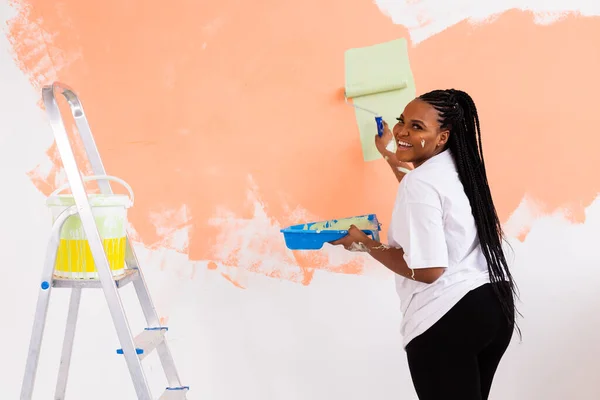 Güzel Afro-Amerikan ev hanımı duvar boyuyor. Yenileme, dekorasyon ve onarım konsepti. — Stok fotoğraf