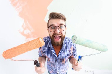 Kapalı mekanda resim yapan komik bir adam. Dekorasyon, yenileme, apartman onarımı ve ferahlatıcı konsept.