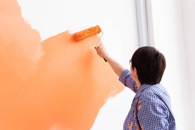 Apartmanda tamirat var. Mutlu orta yaşlı kadın duvarı boyuyor..