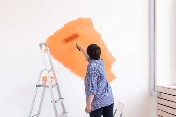 Felice donna di mezza età pittura muro nel suo nuovo appartamento. Concetto di ristrutturazione, ridecorazione e riparazione. — Foto Stock