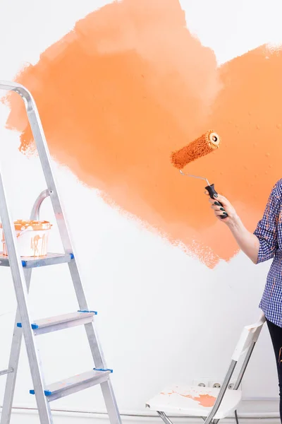 Reparation i lägenheten. Närbild av kvinnan målar väggen med färg. — Stockfoto