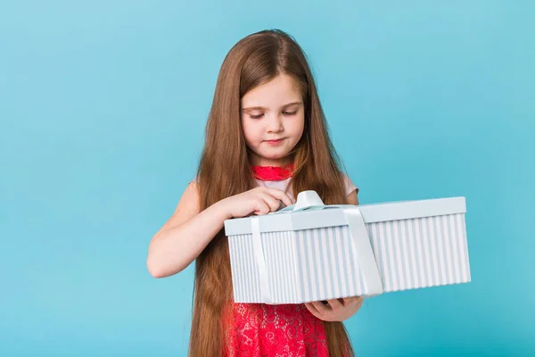 Feliz niña abriendo caja de regalo sobre un fondo azul. En Navidad. Cumpleaños de los niños . — Foto de Stock
