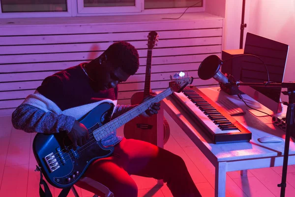 Crear música y un concepto de estudio de grabación - hombre afroamericano guitarrista grabación eléctrica pista de guitarra bajo en el estudio en casa —  Fotos de Stock