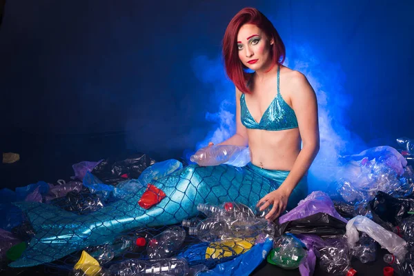 Ocean plastic pollution. Cute mermaid swimming in water with plastic garbage. Stop plastic pollution. Fairy tale and reality concept.