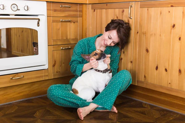 귀여운 강아지 잭을 가진 젊은 여자 가 바닥에 앉아 있는 테리어를 파네요. 애완 동물 과 가정 용품. 집에 있어. — 스톡 사진