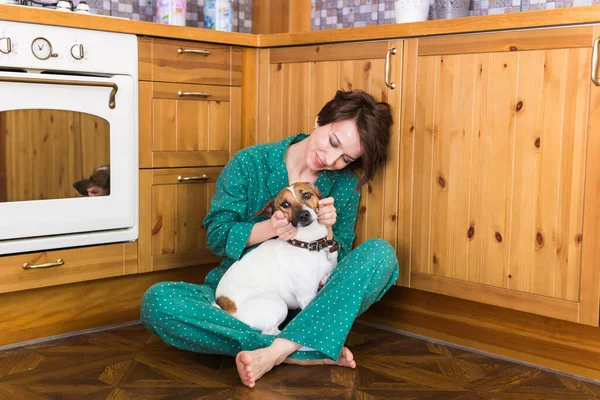 귀여운 강아지 잭을 가진 젊은 여자 가 바닥에 앉아 있는 테리어를 파네요. 애완 동물 과 가정 용품. 집에 있어. — 스톡 사진