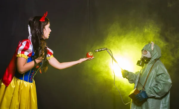Eine als Märchenfigur verkleidete Frau hält ein Warnsymbol für radioaktive atomare ionisierende Strahlung auf einem Apfel. Kern- und Strahlenmesskonzept. — Stockfoto