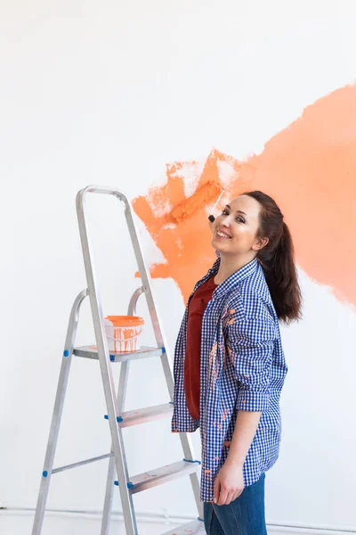 Hermosa mujer pintando la pared. Concepto de renovación, redecoración y reparación. — Foto de Stock