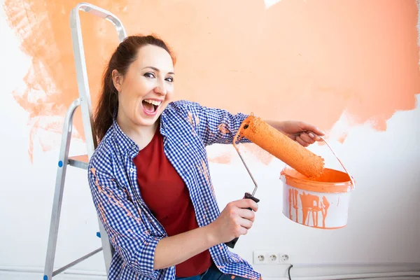 Funny young woman painting wall in her new apartment. Renovation, redecoration and repair concept. — Stock Photo, Image