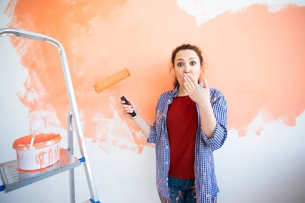 Duvarı boyayan komik kadın. Yenileme, dekorasyon ve onarım konsepti. — Stok fotoğraf