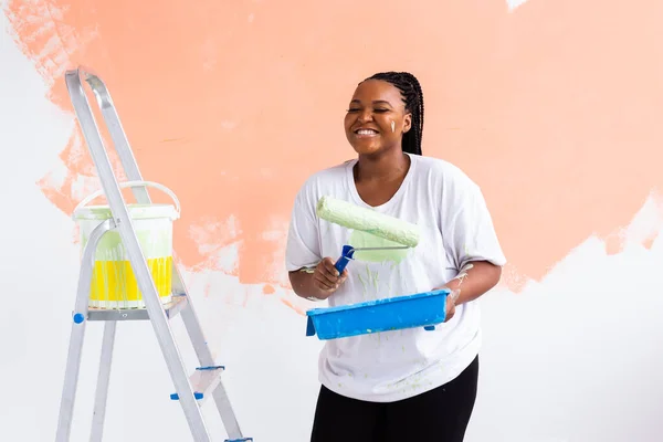 Güzel Afro-Amerikan ev hanımı duvar boyuyor. Yenileme, dekorasyon ve onarım konsepti. — Stok fotoğraf
