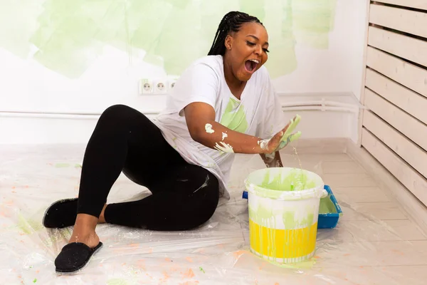 Yeni dairesinde duvar boyayan komik Afrikalı Amerikalı kadın. Yenileme, dekorasyon ve onarım konsepti. — Stok fotoğraf