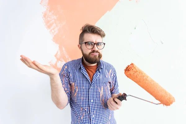 Repair in the apartment. Funny confused man paints the wall with paint. — Stock Photo, Image