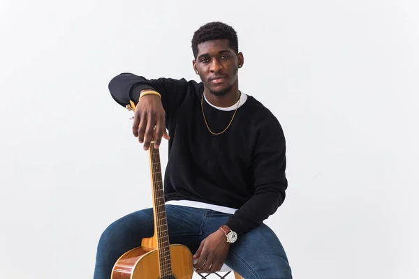 Youth street fashion concept - Portrait of confident sexy black man with guitar in stylish sweatshirt on white background. — Stock Photo, Image