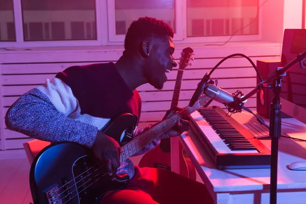 Африканський американський професійний музикант записує бас-гітару в цифровій студії вдома, концепцію технології виробництва музики. — стокове фото