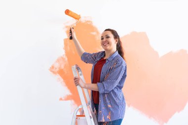 Kapalı mekanda boya pateniyle güzel bir bayan. Dekorasyon, yenileme, apartman onarımı ve ferahlatıcı konsept.