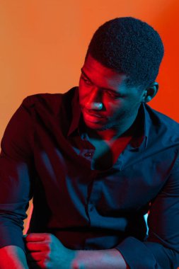 Mavi ve kırmızı ışıklı arka planda poz veren Afro-Amerikan stil adamı.