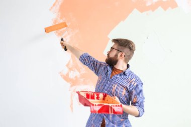 Yenileme, yeniden dekorasyon ve onarım konsepti - yeni evin duvarlarını boyayan neşeli adam.