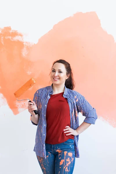 Yenileme, yeniden dekorasyon ve onarım konsepti - Yeni evde duvarları boyayan neşeli kadın.