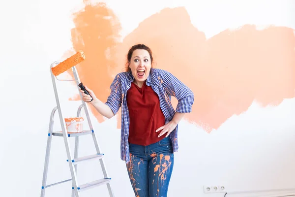 Renovación, redecoración y concepto de reparación - Baile de la mujer divertida pintura de la pared en el nuevo hogar . — Foto de Stock